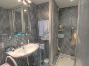 a blue tiled bathroom with a sink and a shower at Apartment Emeraudes by Interhome in Anzère