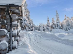 a snow covered forest with a snow covered cabin at Holiday Home Kelovalta 7b by Interhome in Ruka