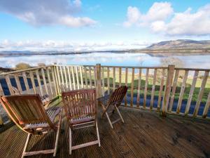 two chairs on a deck with a view of a lake at Chalet Loch Leven Lodge by Interhome in Ballingry