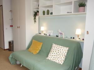 a green couch with two pillows on it in a room at Studio Le Sapin-1 by Interhome in Demi-Quartier
