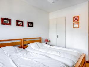 Apartment Fleurs des Alpes-1 by Interhome في سان جيرفيه ليه بان: سرير أبيض في غرفة نوم مع صور على الحائط