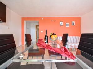 a dining room with orange walls and a glass table at Apartment Milin-1 by Interhome in Jezera