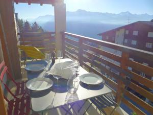un tavolo con piatti e bicchieri da vino su un balcone di Apartment Belmont Est 80 by Interhome a Vermala