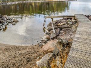 Holiday Home Kainalolahti by Interhome في Kolinkylä: جسر خشبي فوق جزء ماء به صخور