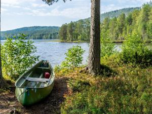 a green canoe sitting on the shore of a lake at Holiday Home Hiisiranta b3 by Interhome in Kolinkylä