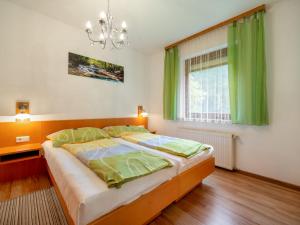 Schlafzimmer mit einem Bett mit grünen Vorhängen und einem Kronleuchter in der Unterkunft Apartment Kleinsee by Interhome in Srejach