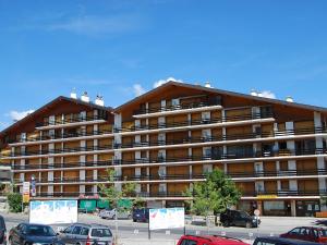 a large building with cars parked in a parking lot at Studio Christiania I R3 by Interhome in Nendaz