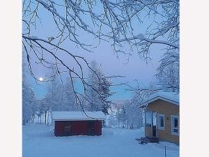 a house is covered in snow next to a house at Holiday Home Huitsin nevada by Interhome in Kangosjärvi