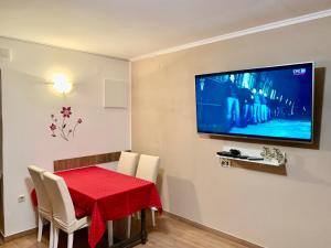 ein Esszimmer mit einem roten Tisch und einem Flachbild-TV in der Unterkunft Apartment in family house Linda in Čavle