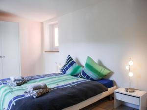 a bedroom with a bed with blue and green pillows at Apartment Busbai by Interhome in Ronco sopra Ascona