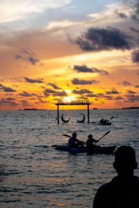 dwoje ludzi pływających kajakiem po oceanie o zachodzie słońca w obiekcie Sky View by Relax Tours w mieście Dhangethi