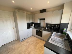 uma cozinha com armários brancos e um balcão preto em Holm from Home em Inverness