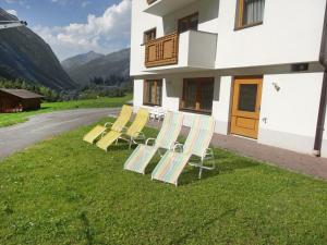 a group of chairs sitting on the grass in front of a building at Apartment Köfels-8 by Interhome in Köfles