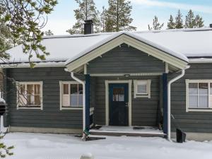 une maison avec une porte bleue dans la neige dans l'établissement Holiday Home Ylläskaira a by Interhome, à Äkäslompolo