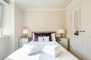 - une chambre blanche avec un lit blanc et des oreillers violets dans l'établissement Stunning 3-bedroom in the heart of London with parking-hosted by Sweetstay, à Londres