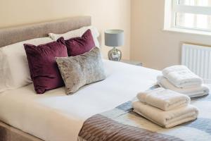 a bed with purple pillows and towels on it at Stunning 3-bedroom in the heart of London with parking in London