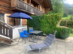 une terrasse avec une table, des chaises et un parasol dans l'établissement Apartment Les Hivernants - EG links by Interhome, à Gstaad
