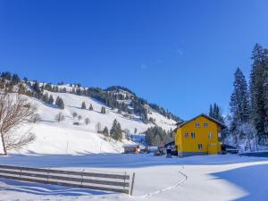 a yellow house in the snow next to a fence at Apartment Chalet Alte Post by Interhome in Schwenden +27 photos