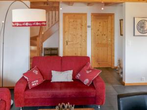 a red couch with pillows in a living room at Chalet Le Muveran V8 by Interhome in Nendaz +46 photos