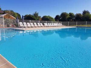 a large swimming pool with chairs and blue water at Apartment Dina with parking and shared pool by Interhome in De Haan