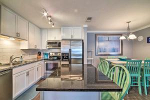 a kitchen with white cabinets and a kitchen island with green chairs at Coastal Condo with Outdoor Pool - Pets Welcome! in Mustang Beach