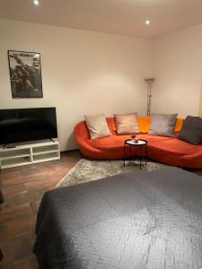 a living room with an orange couch and a flat screen tv at Schöne Zweiraumwohnung im Zentrum in Aue