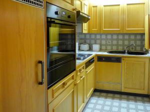 cocina con armarios de madera y nevera de acero inoxidable en Apartment Aiguilles Dorées I-2 by Interhome, en Villars-sur-Ollon