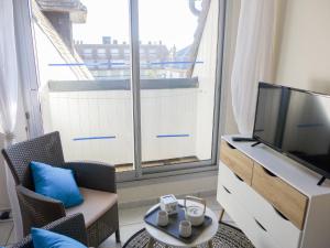 een woonkamer met een tv en een groot raam bij Apartment Le Capricorne by Interhome in Cabourg