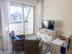 een woonkamer met een tv en een raam bij Apartment Le Capricorne by Interhome in Cabourg