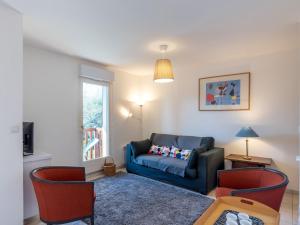 a living room with a blue couch and red chairs at Apartment Domaine de Clairefontaine-3 by Interhome in Deauville