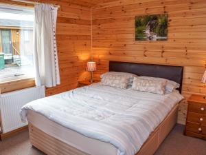 ein Schlafzimmer mit einem Bett in einer Holzwand in der Unterkunft Chalet Osprey Lodge by Interhome in Kinross