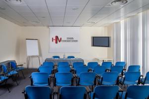 a conference room with blue chairs and a table and a screen at Hotel Mediterraneo in Livorno
