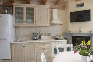 a kitchen with white cabinets and a table and a fireplace at To Petradi in Avgonyma