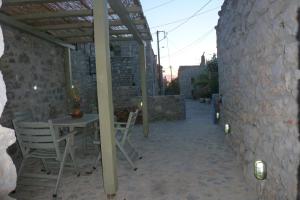 um pátio com uma mesa e cadeiras e uma parede de pedra em To Petradi em Avgonyma
