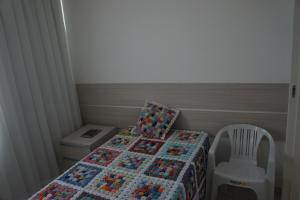 a small bedroom with a bed with a quilt on it at Pajuçara beach - 2 QUARTOS in Maceió +4 photos