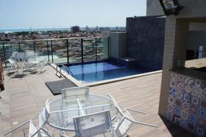 a balcony with chairs and a swimming pool on a building at Pajuçara beach - 2 QUARTOS in Maceió