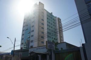 a tall white building with the sun behind it at Pajuçara beach - 2 QUARTOS in Maceió