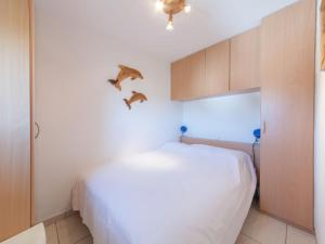 a bedroom with a white bed with birds on the wall at Apartment Firenze 108 with parking by Interhome in Bredene