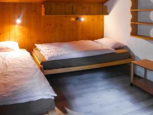two twin beds in a room with wooden walls at Apartment Chalet l'Aube by Interhome in Vers L'Eglise