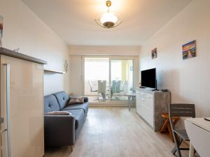 ein Wohnzimmer mit einem blauen Sofa und einem TV in der Unterkunft Apartment Plein Sud by Interhome in Cabourg