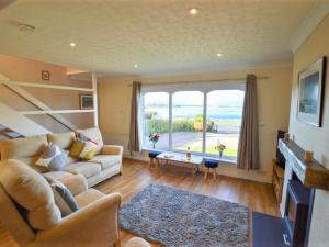 a living room with a couch and a large window at Holiday Home An Cala by Interhome in Oban