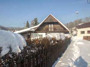 a fence in front of a house covered in snow at Holiday Home Lánov by Interhome in Horní Lánov