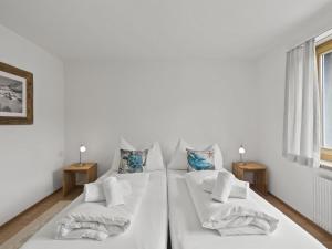 a white room with two beds and two tables at Apartment Bellavista 6 by Interhome in Parpan