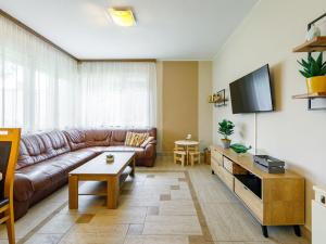 salon z brązową skórzaną kanapą i telewizorem w obiekcie Holiday Home Marian by Interhome w mieście Balatonboglár