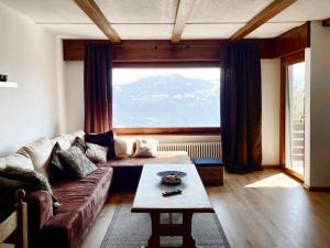 a living room with a couch and a large window at Apartment Lisière-Sud by Interhome in Crans-Montana