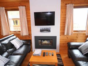 Chalet Loch Leven Lodge 11 by Interhome في كينروس: غرفة معيشة مع كنبتين جلديتين ومدفأة
