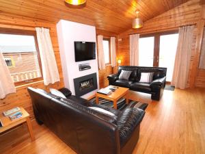sala de estar con muebles de cuero y TV de pantalla plana en Chalet Loch Leven Lodge 11 by Interhome, en Kinross