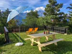 a picnic table with two chairs and an umbrella at Chalet Chalet Chante Neige by Interhome in Riddes