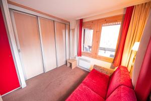 sala de estar con sofá rojo y ventana en Le Panoramix en Plagne 1800