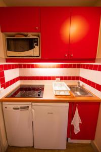 a kitchen with red cabinets and a sink and a microwave at Le Panoramix in Plagne 1800